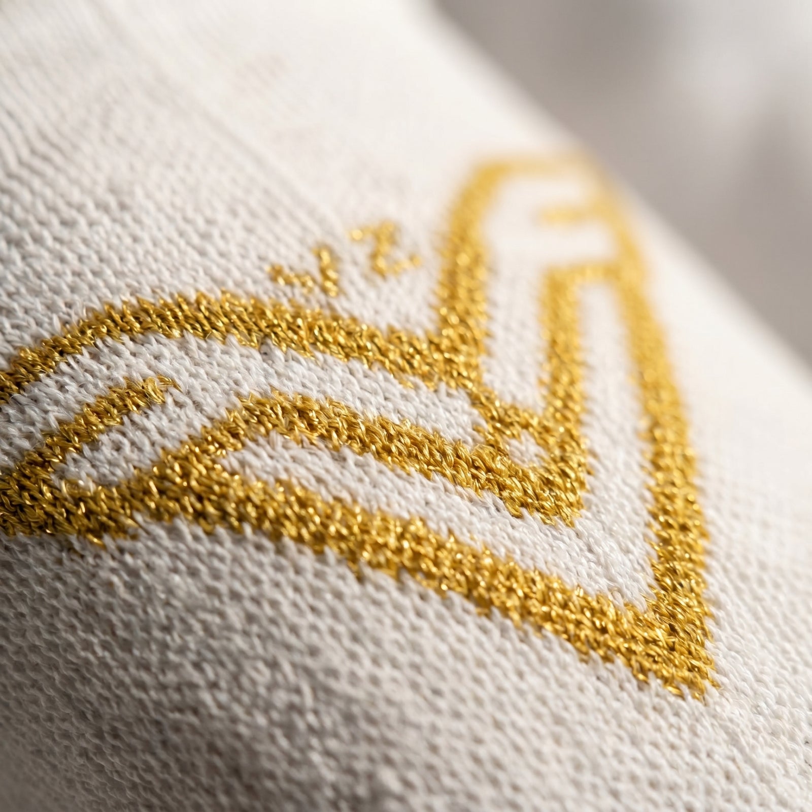 Close-up of a gold embroidered design on white fabric