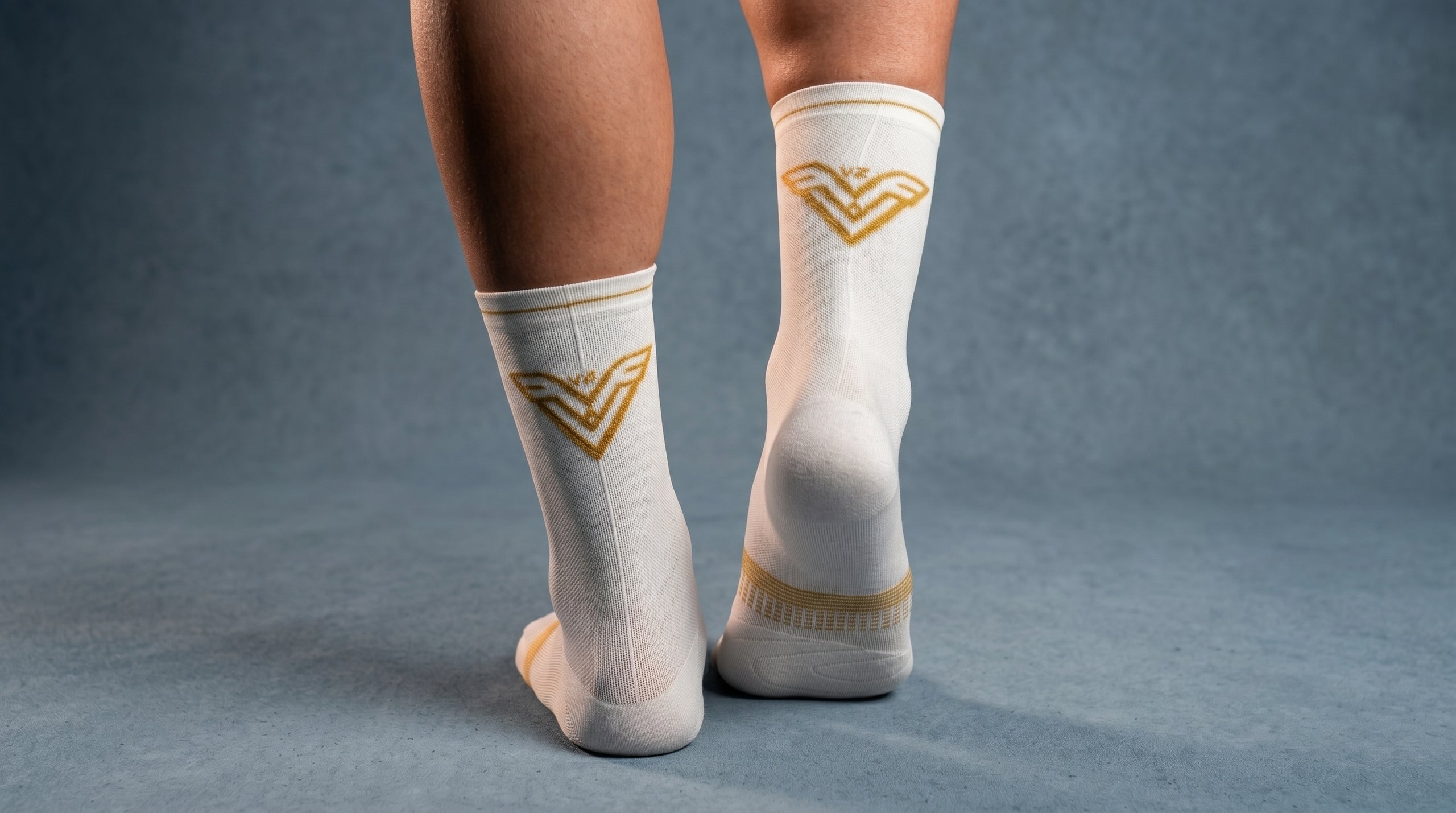 White socks with gold symbols worn by a person on a gray background